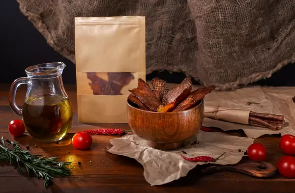 Beef jerky served in a wooden bowl with chillies and oil